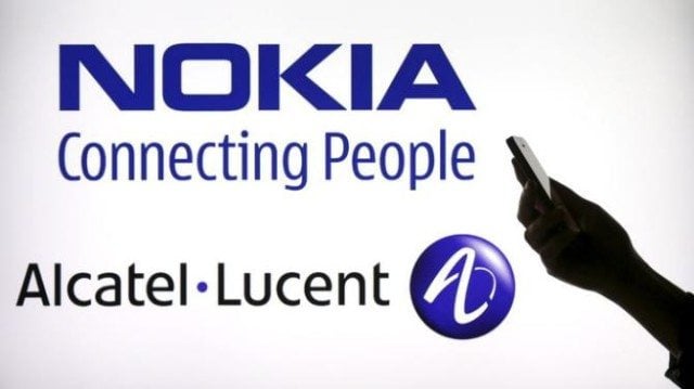 Photo illustration of a woman holding a smartphone in front of a screen displaying both Nokia and Alcatel Lucent logos in Paris